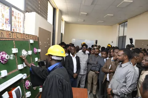 image of a crowd gathering in a room watch a demonstration of lighting by a person with safety helmet on