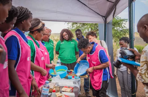 Image of a group of trainee watching a demonstration from one instructor in an outdoor tent
