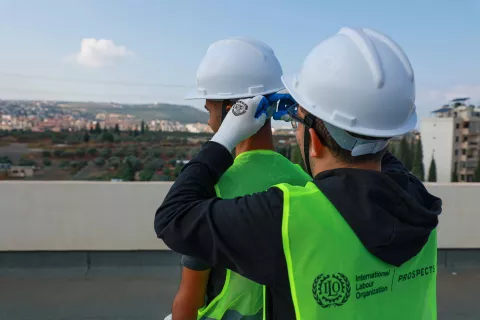 Image of one EIIP worker helping the other fasten the safety helmet