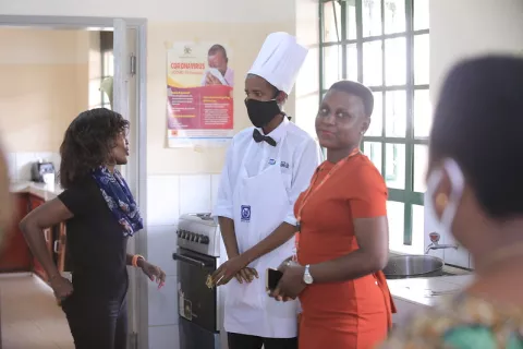 Image of three people, one of them dressed in a chef's uniform talking to the others
